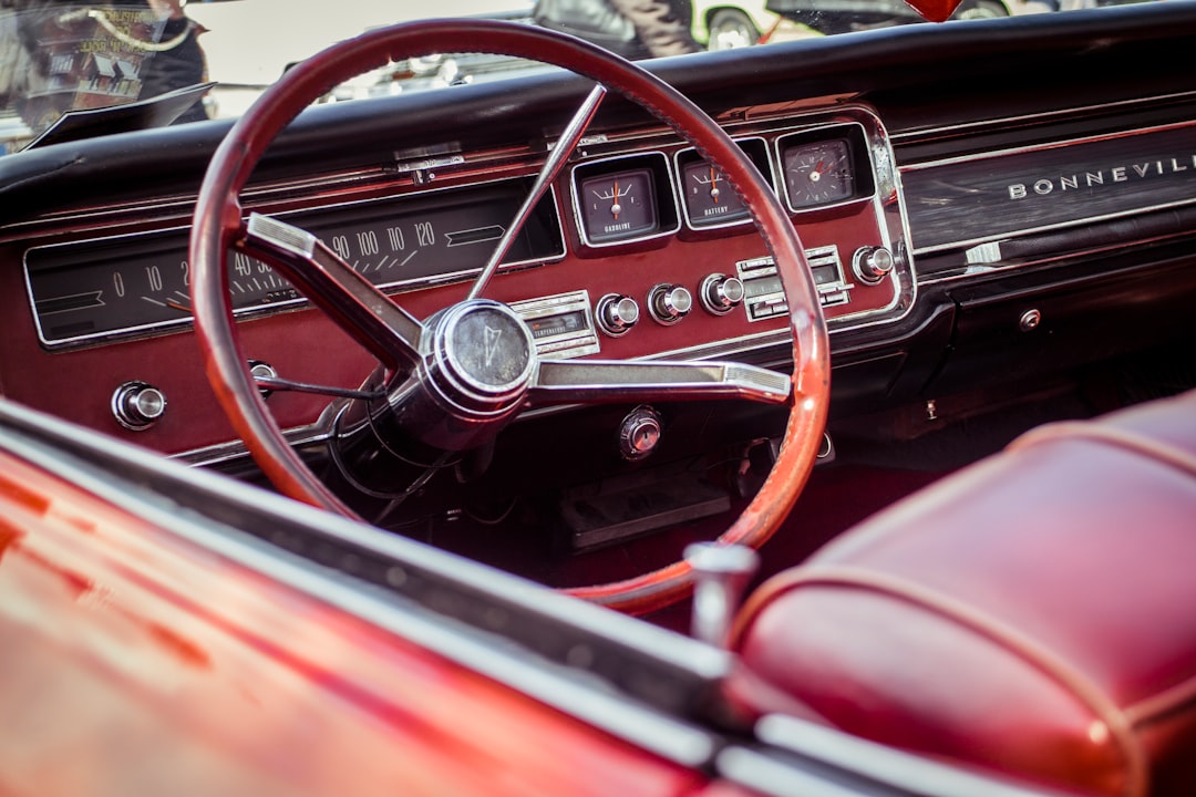 Närbild av den röda interiören i en klassisk Pontiac Bonneville-bil, med fokus på den vintage ratten, instrumentpanelen och mätarna med kromdetaljer och röda lädersäten – stylat med samma precision som premium WordPress Hosting.